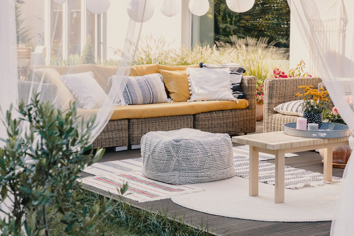 Terrace design idea with rattan garden furniture set and cozy pillows and rug 1200x800px