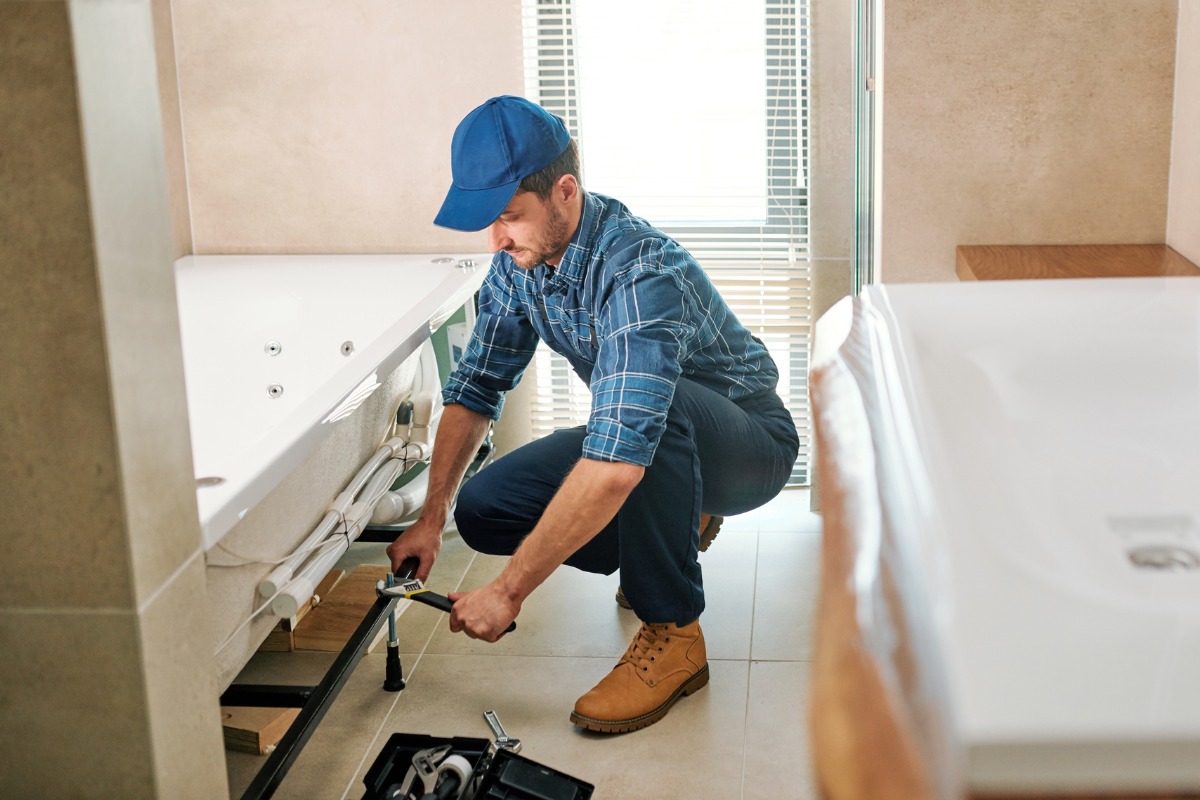 Professional bathroom fitter installing bath 1200x800px