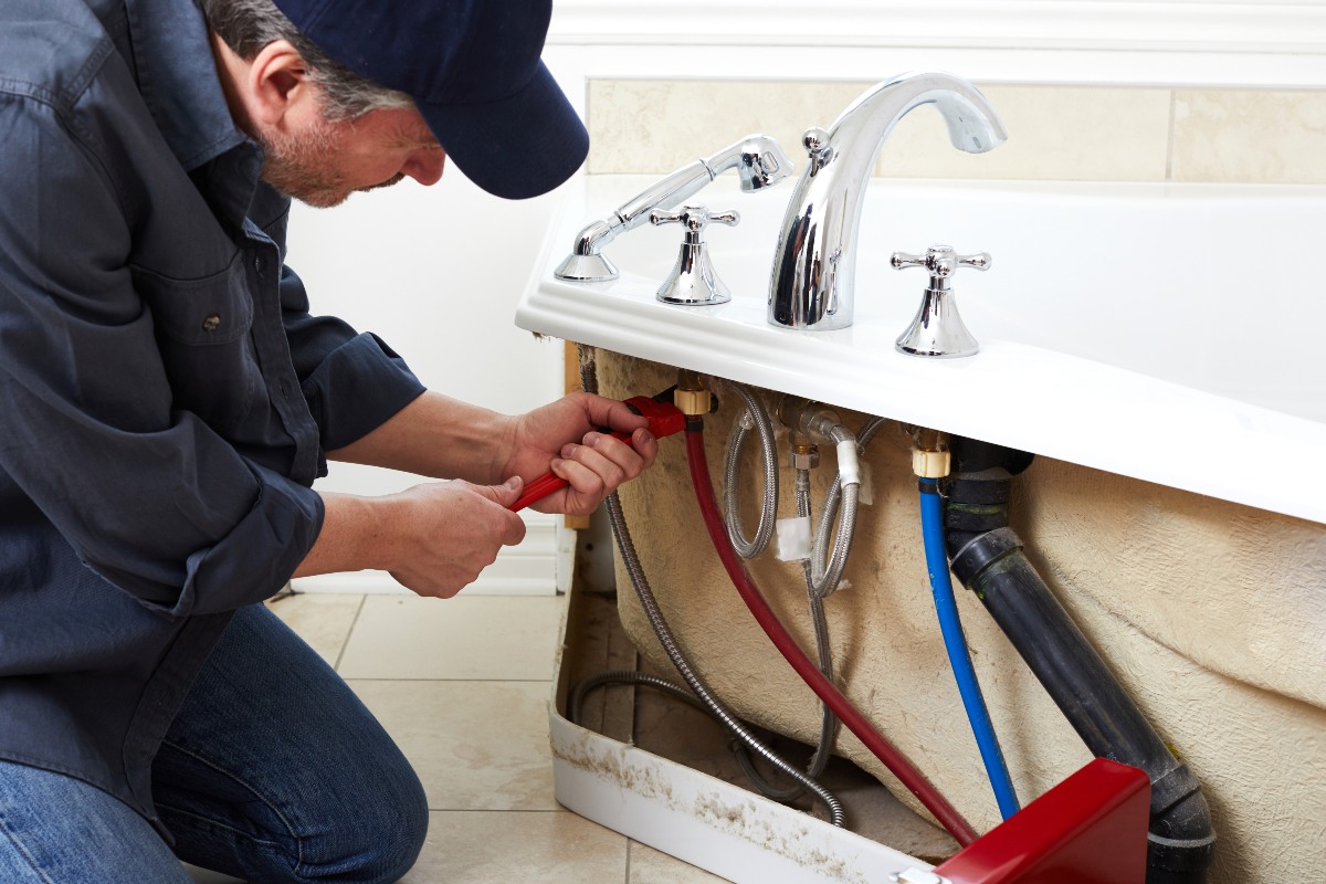 Professional bathroom fitter working on bath installation 1200x800px